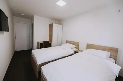 two beds in a hotel room with a television at Hotel Tanja in Banja Luka