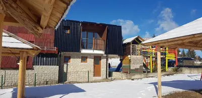 a building with a playground in the snow at Apartman za dvoje in Vlasic