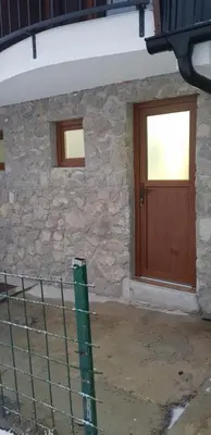 a stone house with a wooden door and a fence at Apartman za dvoje in Vlasic