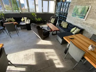 a restaurant with couches and tables and windows at Hostel Mornar in Velika Kladuša