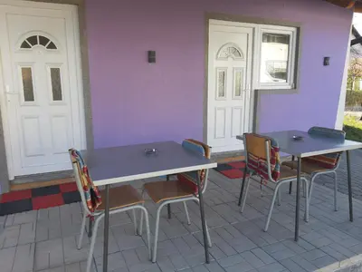 two tables and chairs in front of a purple wall at SubotićSmještaj in Kulaši