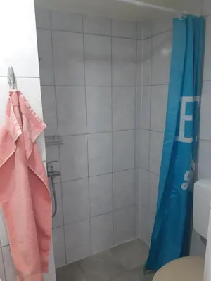 a bathroom with a shower with a blue shower curtain at SubotićSmještaj in Kulaši