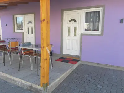 a house with a purple wall and a table and chairs at SubotićSmještaj in Kulaši