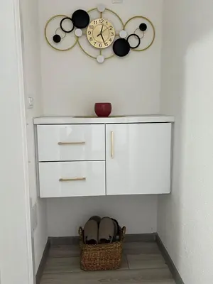 a clock on a wall above a cabinet with shoes at Apartment Nostra Aula in Travnik