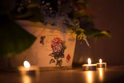 a table with two candles and a vase with flowers at Gradiska na Savi apartmani i sobe in Bosanska Gradiška