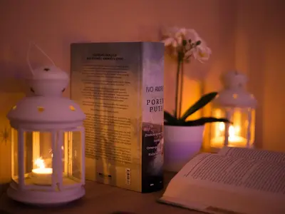 a book sitting on a table next to a candle and a book gmaxwell gmaxwell gmaxwell at Gradiska na Savi apartmani i sobe in Bosanska Gradiška