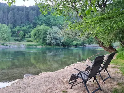 a couple of chairs sitting next to a river at EMRAH RIVER UNA in Bihać