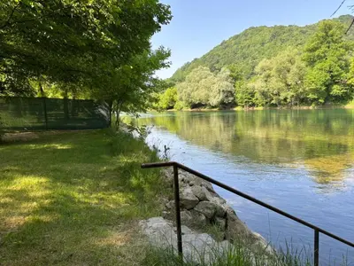a view of a river with trees and a fence at EMRAH RIVER UNA in Bihać