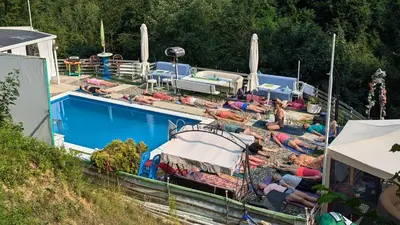 a group of people laying around a swimming pool at tree house in Visoko