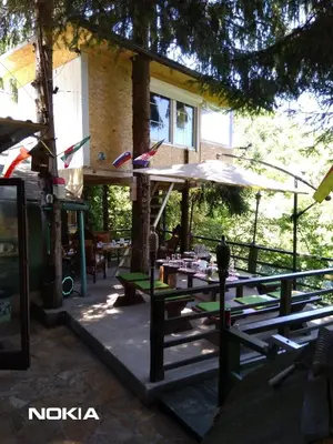 a patio with tables and an umbrella in front of a building at tree house in Visoko
