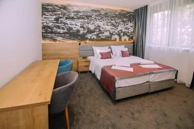 a hotel room with a bed and a desk and a bed sidx sidx sidx sidx at Hotel Salis in Tuzla
