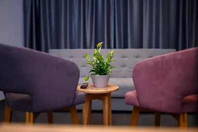 a living room with two purple chairs and a plant on a table at Hotel Salis in Tuzla