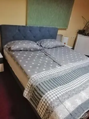 a bed with a blue headboard and pillows on it at Nik-rom in Bosanska Gradiška
