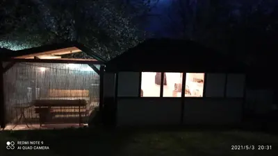 a gazebo with a bench in a yard at night at Ravne Apartman 2 in Visoko