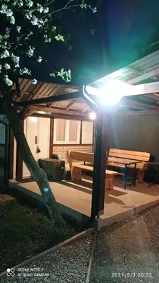 a building with a pavilion with a picnic table and a tree at Ravne Apartman 2 in Visoko