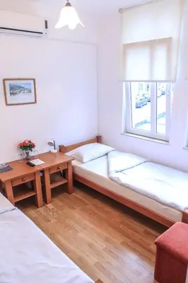 a room with two beds and a table and a window at Pansion Centar in Tuzla