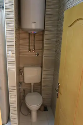 a small bathroom with a toilet and a water tank at Pansion Centar in Tuzla