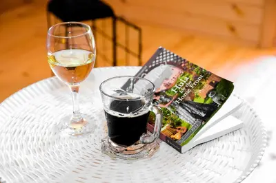 a glass of wine and a book on a table at Cottage Lana in Jajce
