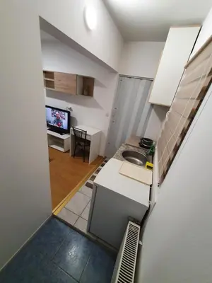 a small kitchen with a sink and a tv at Garsonjera u centru Prnjavor in Prnjavor