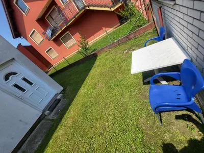 a table and a blue chair in a yard at Garsonjera u centru Prnjavor in Prnjavor