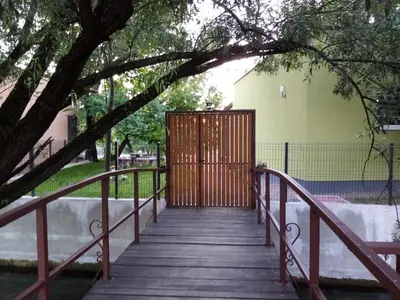 a wooden walkway with a wooden gate under a tree at Apartman Dzenis in Bihać