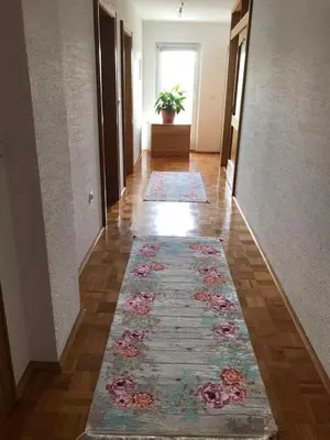 a hallway with a rug on the floor and a hallway with a flower rug at Sobe Lara in Gradačac