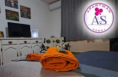 a bedroom with a bed with an orange blanket on it at Stan na dan AS Doboj in Doboj