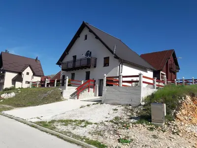 a large white house with a black roof at Adria in Kupres