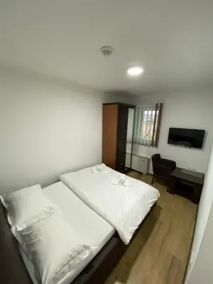 a bedroom with a bed with white sheets and a desk at Motel OAZA in Cazin