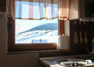 a kitchen window with a view of a snow covered field at Apartman Adria 2 in Kupres