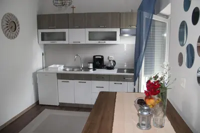 a kitchen with white cabinets and a table with flowers on it at Apartman ANA Livno - biker friendly in Livno