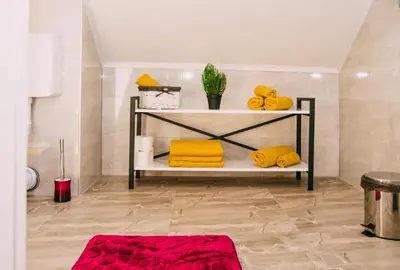 a bathroom with yellow towels on a shelf at Apartmani Markešić Ramsko jezero in Prozor
