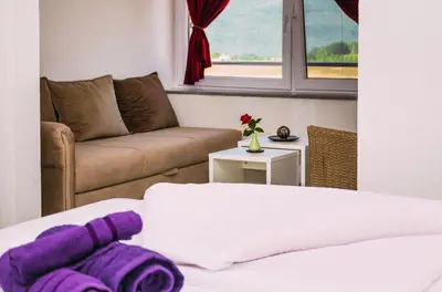a living room with a couch and a bed and a window at Apartmani Markešić Ramsko jezero in Prozor