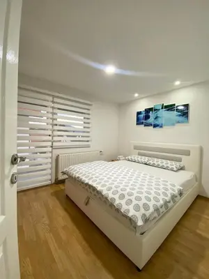 a white bedroom with a bed and a window at Apartmani GO Bugojno in Bugojno
