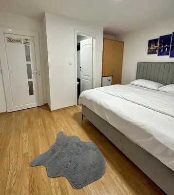 a bedroom with a bed and a rug on a wooden floor at Apartmani GO Bugojno in Bugojno