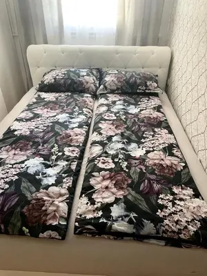 a bed with a floral comforter on it at Apartman CITY CENTER 1-šetalište in Prijedor