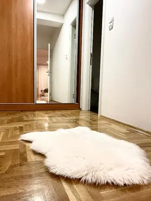 a white rug on the floor in a room with a mirror at Apartman CITY CENTER 1-šetalište in Prijedor