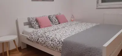 a bedroom with a bed with pink and grey pillows at Elena apartmani in Tuzla