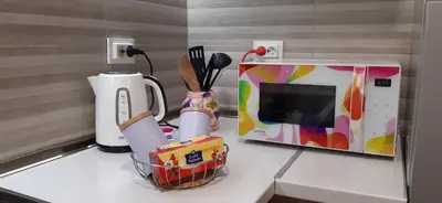 a kitchen counter with a microwave and a basket of utensils at Elena apartmani in Tuzla