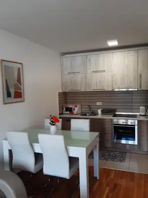 a kitchen with a white table and white chairs at Elena apartmani in Tuzla