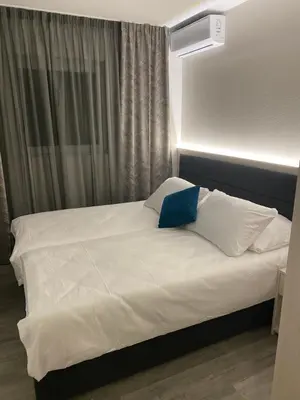 a bed with a blue pillow on top of it at DM Sobe in Tuzla