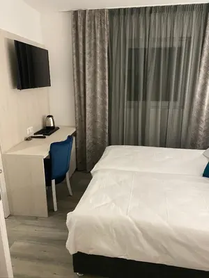 a hotel room with a bed and a desk with a television at DM Sobe in Tuzla