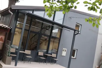a glass extension of a building with tables and chairs at DM Sobe in Tuzla
