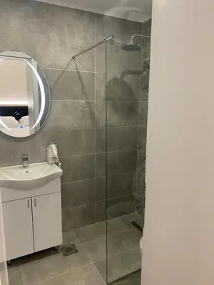 a bathroom with a shower with a sink and a mirror at DM Sobe in Tuzla