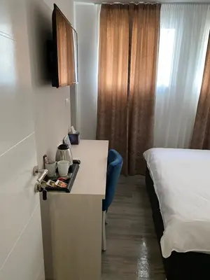 a hotel room with a desk and a bed and a room at DM Sobe in Tuzla