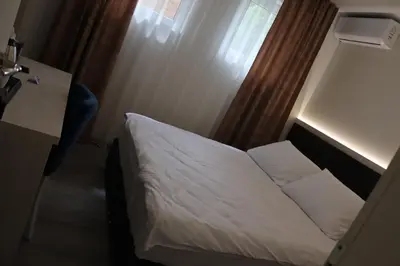 a hotel room with a bed and a desk and window at DM Sobe in Tuzla