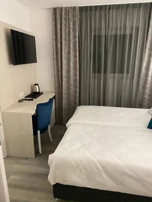 a hotel room with a bed and a desk with a computer at DM Sobe in Tuzla