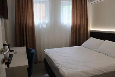 a bedroom with a bed and a table and a window at DM Sobe in Tuzla