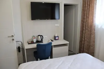 a room with a bed and a desk with a television on the wall at DM Sobe in Tuzla
