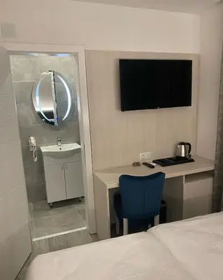 a room with a bed and a desk and a television at DM Sobe in Tuzla